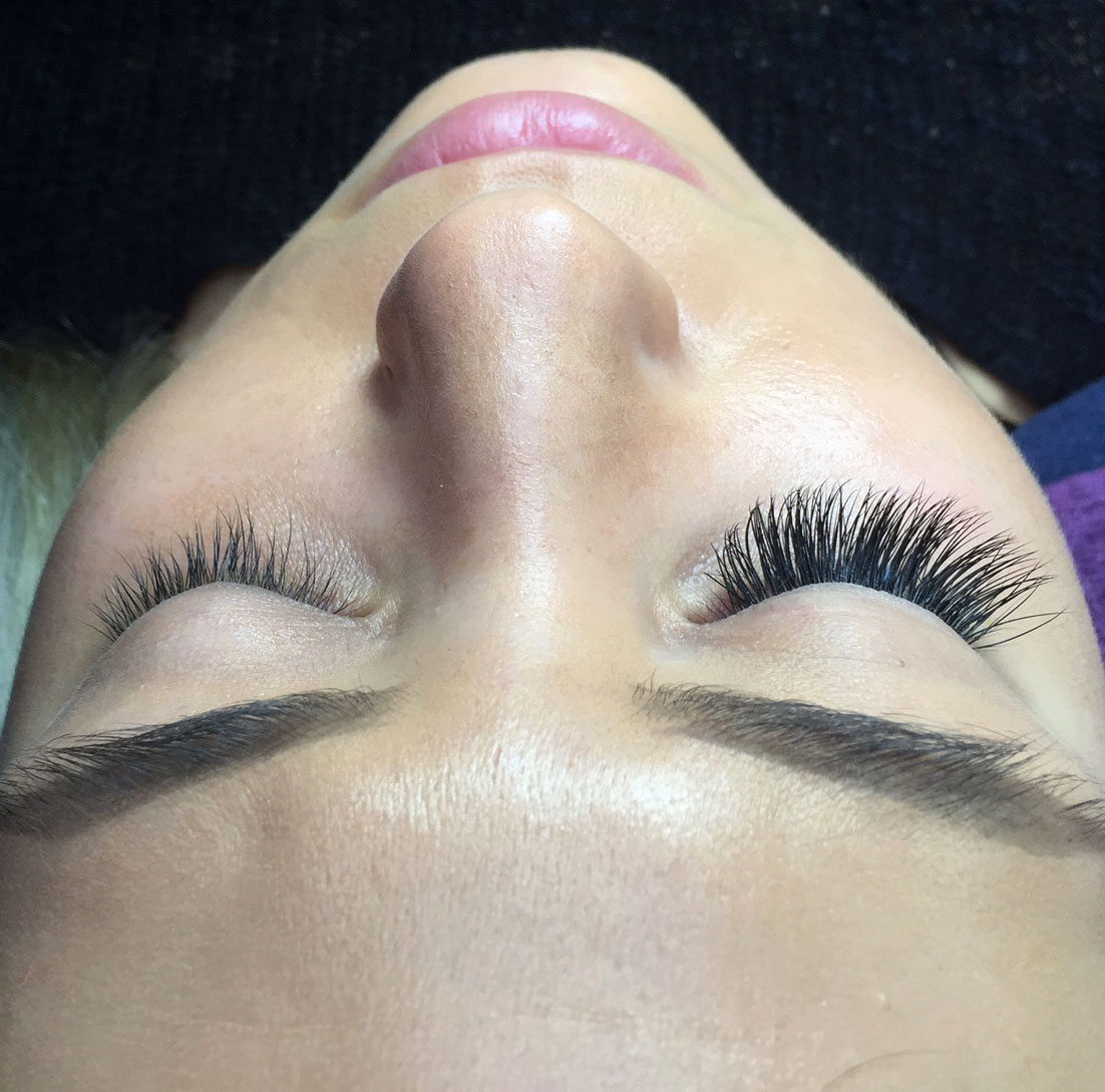 A photo of a woman with one eye lash extension, the other normal